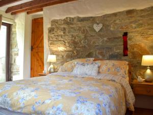 ein Schlafzimmer mit einem Bett mit einer Steinwand in der Unterkunft Old Chapel Cottage - Dinas Country Club in Dinas