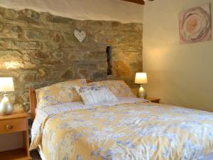 ein Schlafzimmer mit einem Bett und einer Steinwand in der Unterkunft Old Chapel Cottage - Dinas Country Club in Dinas + 10 Fotos