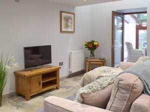 ein Wohnzimmer mit einem Flachbildfernseher auf einem Tisch in der Unterkunft Bluebell Cottage - Uk12988 in Monington