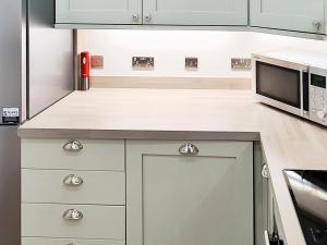 una cucina con mobili bianchi e un forno a microonde di Inchkeith View a Edimburgo