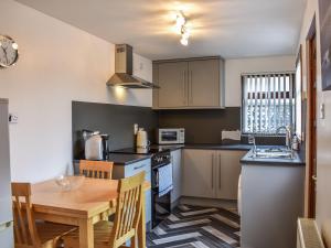 cocina con mesa de madera y cocina con comedor en Belger Cottage, en Inverallochy