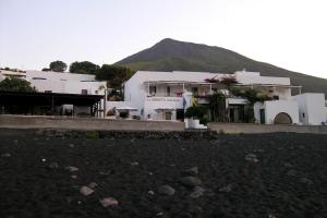 a group of white buildings with a mountain in the background at La Sirenetta Park Hotel in Stromboli