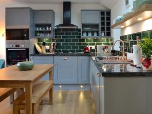 une cuisine avec des placards bleus et une table en bois dans l'établissement Howe Cottage, à Laurencekirk