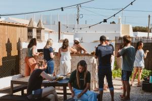 a group of people preparing food on a patio at Aldeia Caiçara Surf House in Sagres