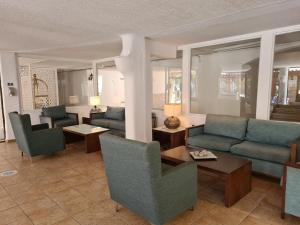 Una sala de estar con sofás y sillas y una mesa. en Basilica Holiday Resort, en Pafos