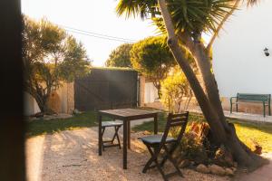 a table and a chair next to a palm tree at Aldeia Caiçara Surf House in Sagres