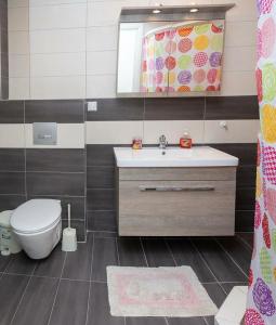 a bathroom with a sink and a toilet and a mirror at Villa Afrodite in Néa Péramos