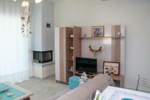 a living room with a couch and a flat screen tv at Villa Afrodite in Néa Péramos