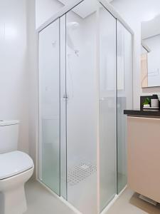 a white bathroom with a glass shower stall at Studio Premium em Torres - 450mts da Praia da Cal - Ar condicionado - Tv Smart - Wifi - Garagem - Aceita Pet in Torres