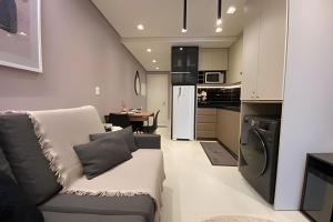 a living room with a couch and a kitchen at Studio Premium em Torres - 450mts da Praia da Cal - Ar condicionado - Tv Smart - Wifi - Garagem - Aceita Pet in Torres +24 photos