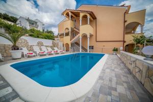 a villa with a swimming pool in front of a house at Apartments Saldun in Trogir