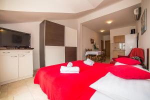a bedroom with two red beds with towels on them at Apartments Saldun in Trogir
