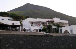 a group of white buildings with a mountain in the background at La Sirenetta Park Hotel in Stromboli