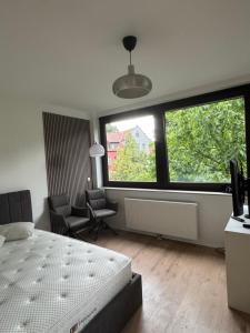 a bedroom with a bed and a chair and two large windows at Deluxe Apartment in Kaisernähe in Porta Westfalica