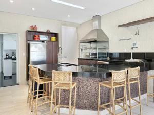 a kitchen with a black counter and chairs in it at 1 Suite - Churrasqueira - Piscina - AC - 200m do mar in Guarujá