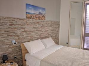 un letto in una camera da letto con muro di mattoni di Punta mare a Marsala