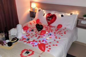 una cama con corazones rojos y confeti. en Apê Inteiro| 2Qts| Estacionamento| Wi-Fi 350| Pet Friendly| Ao Lado do Parque das CEREJEIRAS, en Campos do Jordão