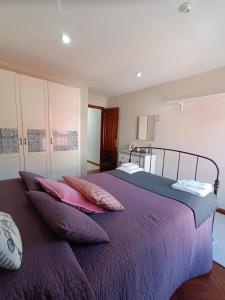 ein Schlafzimmer mit einem lila Bett mit Kissen darauf in der Unterkunft Piso A Capela con vistas al mar in Fisterra