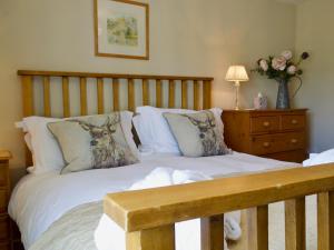 a bedroom with a bed with white sheets and pillows at Periwinkle Cottage in Great Longstone