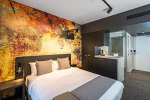 a hotel room with a bed and a painting on the wall at Kennigo Hotel Brisbane in Brisbane