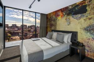 a bedroom with a large bed and a large window at Kennigo Hotel Brisbane, Independent Collection by EVT in Brisbane