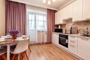 a kitchen with white cabinets and a table with chairs at 1-комнатная квартира Иманбаевой 2, ЖК Байконыс in Astana