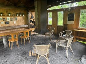 a cabin with a fireplace and chairs and a stove at Näckros in Filipstad