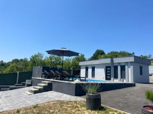 a house with a swimming pool and an umbrella at Vikendica Oaza in Babići
