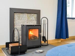 a fireplace in a living room with a stone wall at Druids Knowe in Tarfside