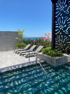 a row of chairs sitting next to a swimming pool at Suite Privada frente a Vidanta Queen in Nuevo Vallarta