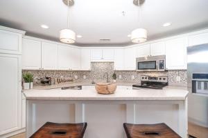 a kitchen with white cabinets and a counter with two stools at Waterfront Resort , World Class Marina & Slip in Beaufort