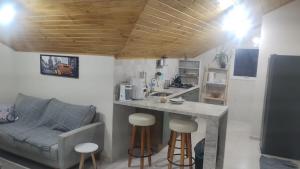 a kitchen with a counter with stools and a couch at Ametista Apartment in Nova Petrópolis