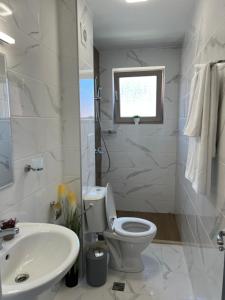 a white bathroom with a toilet and a sink at Apartment D25 Pomorie in Pomorie +7 photos
