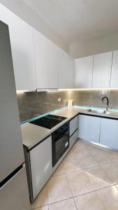 a kitchen with white cabinets and a stove top oven at Leo apartaments with sea view in Durrës