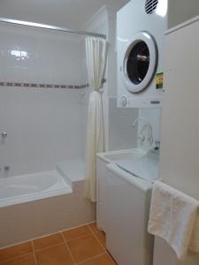 a white bathroom with a tub and a sink at Lifestyle Apartments at Ferntree in Fern Tree Gully