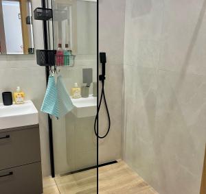 a shower with a glass door next to a sink at Apartament SOLMARINA in Iława +6 photos