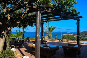 a wooden pergola with tables and chairs on a patio at Tethys Apartments Karfas in Chios