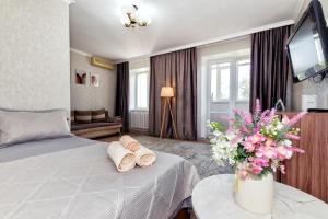 Una habitación de hotel con una cama y un jarrón de flores. en 1-комнатная квартира Республики-Кенесары, en Astana