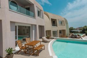 a house with a swimming pool and chairs and a table at Tortuga Luxury Villas Sivota in Syvota