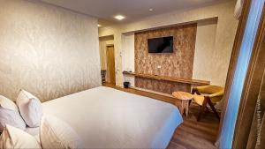 a bedroom with a white bed and a television at Hotel Bankir Khiva in Khiva