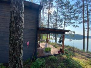 a cabin with a deck next to a tree at Jazinka Sunrise 2 in Apšenieki +14 photos