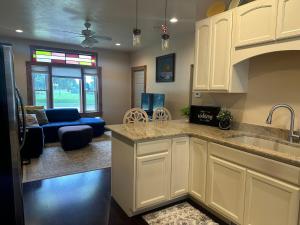 a kitchen with white cabinets and a living room at Charming Brick House in Little Chute