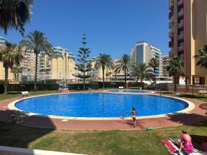 a woman is standing in front of a swimming pool at La Manga del Mar Menor, Los Miradores del Puerto in La Manga del Mar Menor