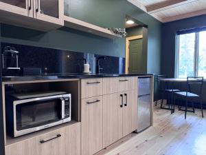 a kitchen with wooden cabinets and a microwave and a table at Auberge Valcartier - Par Aneyro in Saint-Gabriel-De-Valcartier