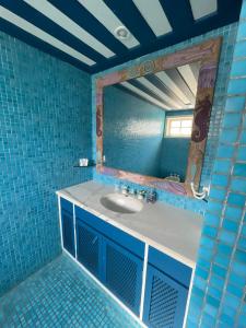 a blue tiled bathroom with a sink and a mirror at Casa da Tartaruga Búzios in Búzios