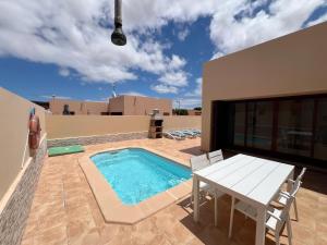 eine Terrasse mit Tisch und Swimmingpool in der Unterkunft Anahi Homes Corralejo - Villa Dracaena 2 in La Oliva