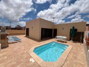 eine Terrasse mit Swimmingpool und einem Haus in der Unterkunft Anahi Homes Corralejo - Villa Dracaena 2 in La Oliva