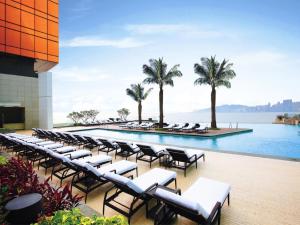 een zwembad met ligstoelen en palmbomen op een gebouw bij MGM Macau in Macau