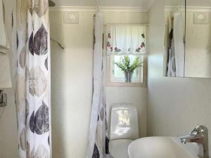 a bathroom with a toilet and a sink and a window at Charming Garden Cottage in Levide in Hemse