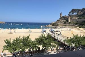 a group of people walking on a beach near the ocean at LETS HOLIDAYS Wake Up by the Sea in Victoria apartment 2 in Tossa de Mar